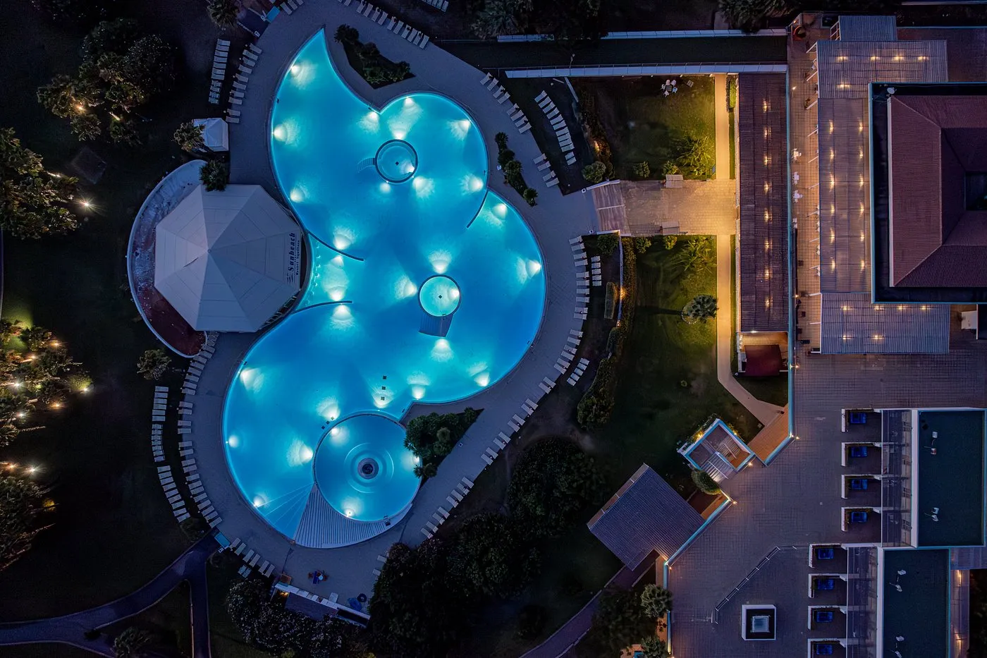 Vista aerea notturna della piscina illuminata di blu a forma di trifoglio