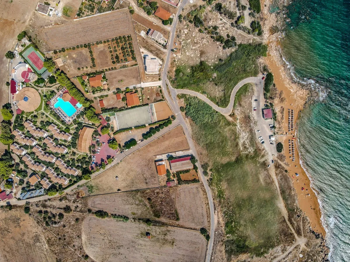 Vista aerea del resort con campi sportivi, piscina e costa con spiaggia