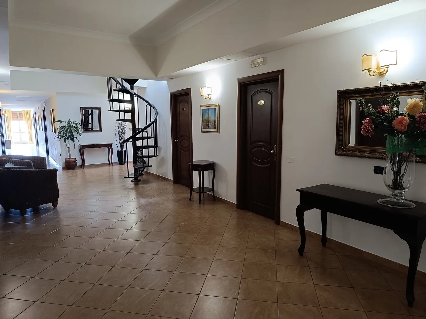 Hall dell'hotel con scala a chiocciola, pavimento in cotto e arredi eleganti