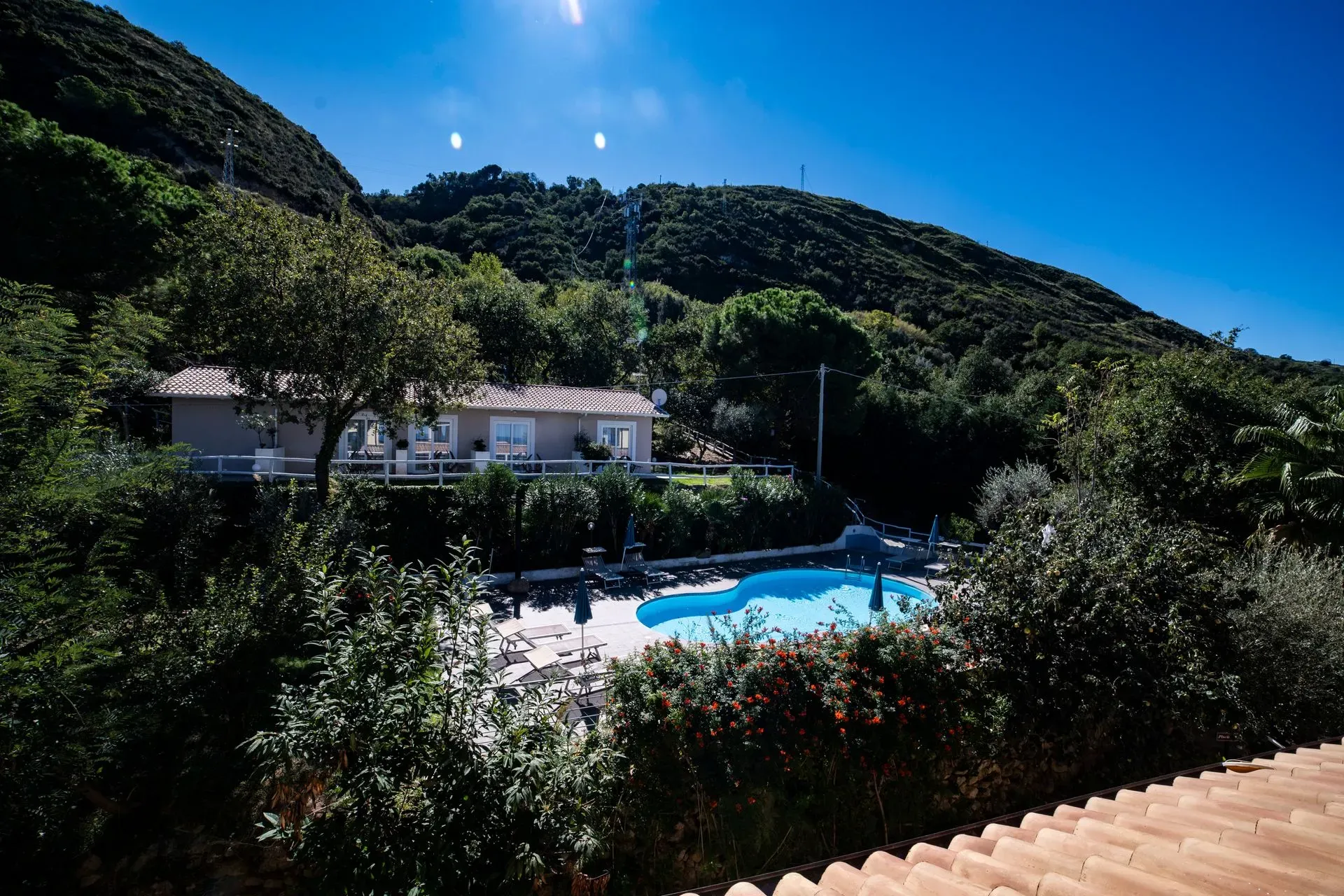 Piscina immersa nel verde collinare con lettini e dependance