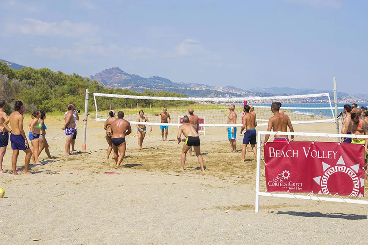 Partita di beach volley sulla spiaggia con il mare e le montagne sullo sfondo