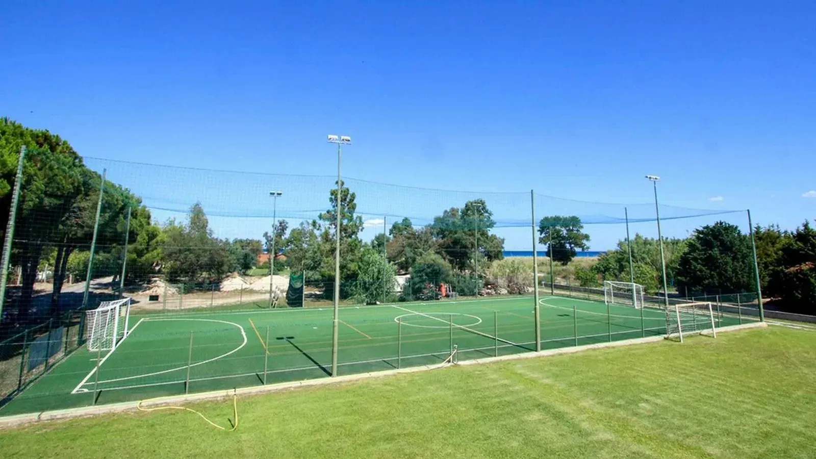 Campo sportivo polivalente con erba sintetica e mare sullo sfondo