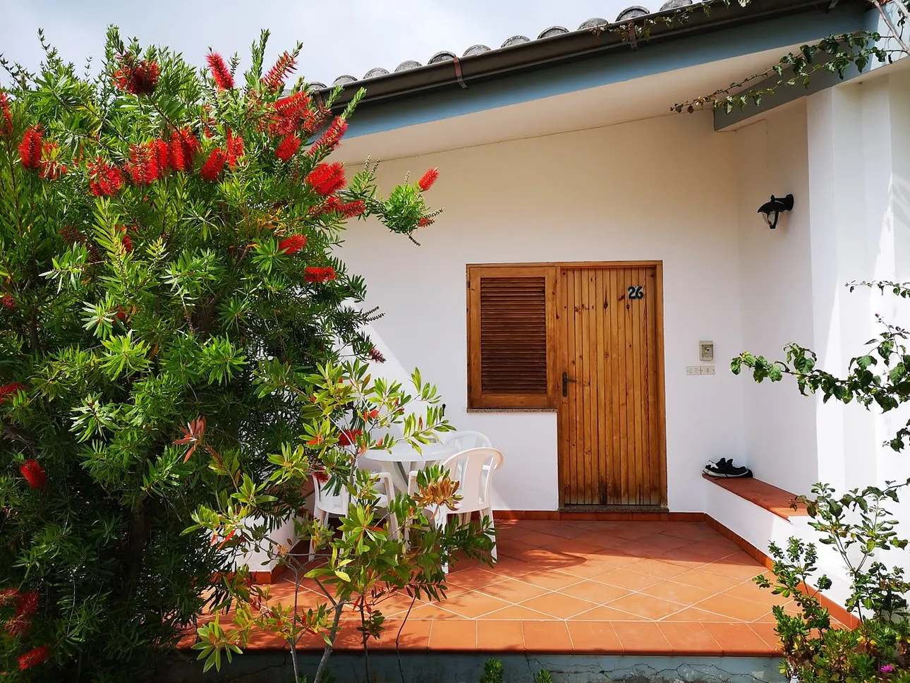 Ingresso di una camera con patio in cotto, tavolino e piante fiorite