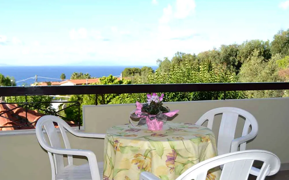 Balcone con tavolino, sedie e vista panoramica sul mare e sul verde