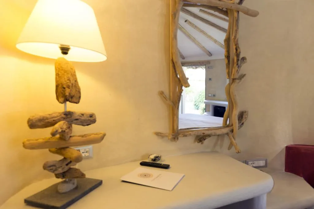 Dettaglio di camera con lampada e specchio in legno di mare su parete chiara