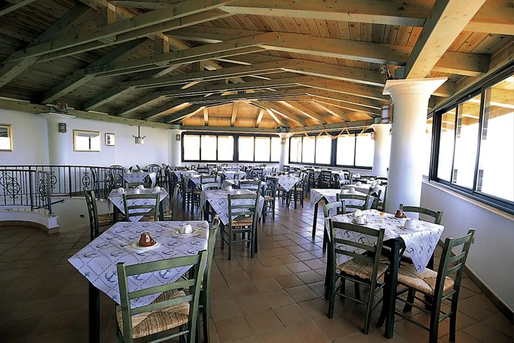 Sala ristorante con soffitto in legno a vista, tavoli apparecchiati e sedie in stile rustico
