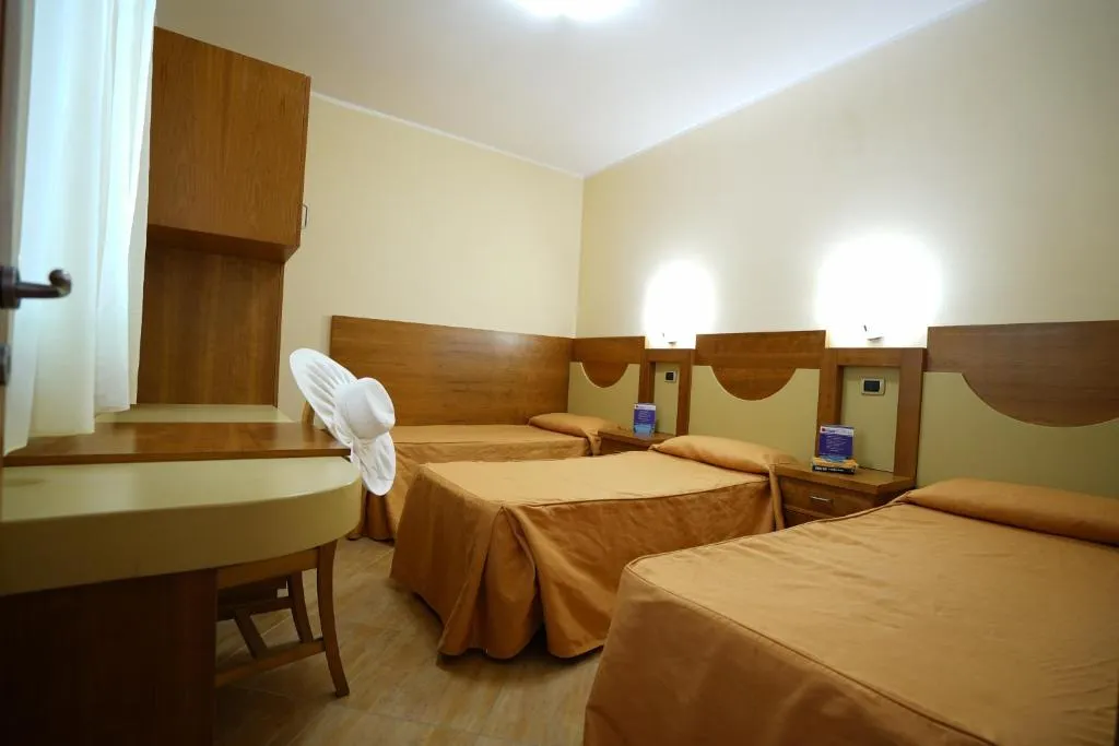 Camera tripla con tre letti singoli, scrivania e arredo in legno