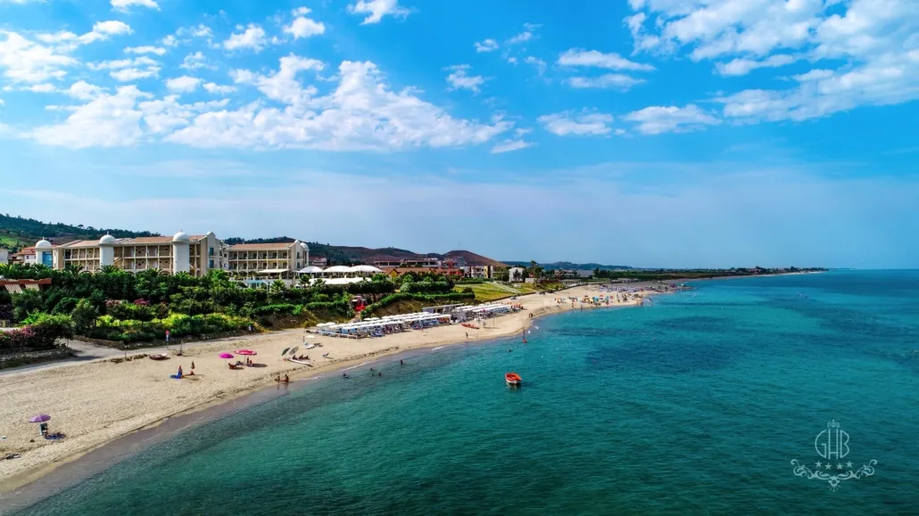 Vista aerea della spiaggia sabbiosa con ombrelloni, hotel e mare turchese
