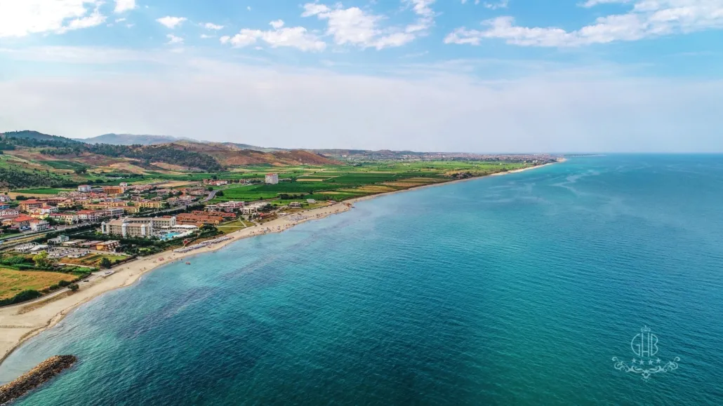 Veduta aerea della costa con spiaggia, hotel e colline verdi sullo sfondo