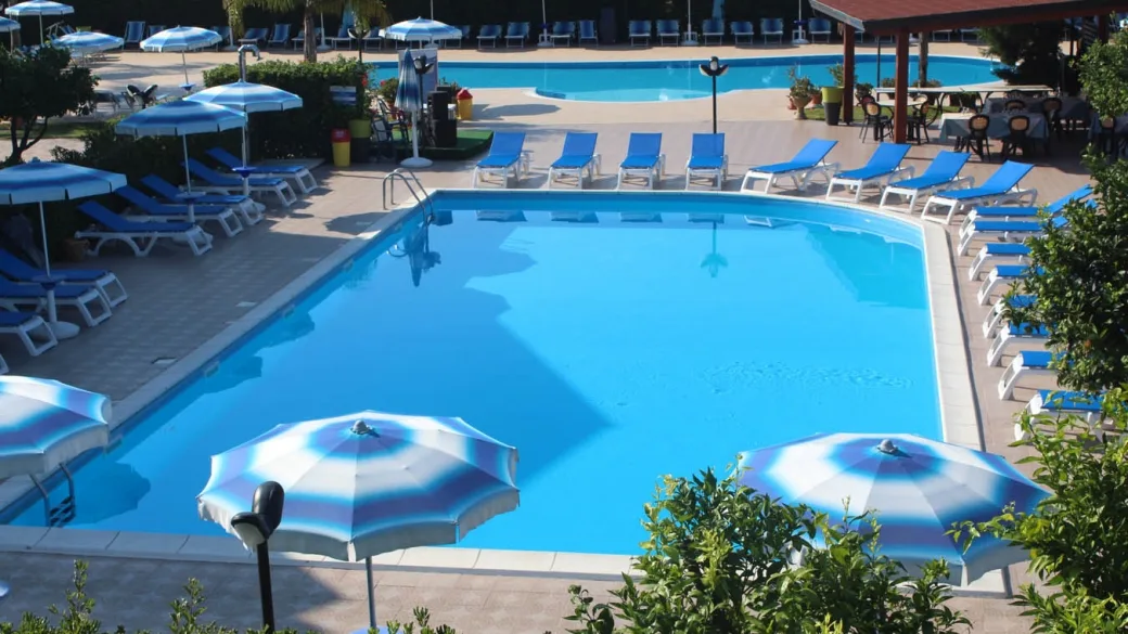 Piscina con lettini blu, ombrelloni e area ristoro all'aperto