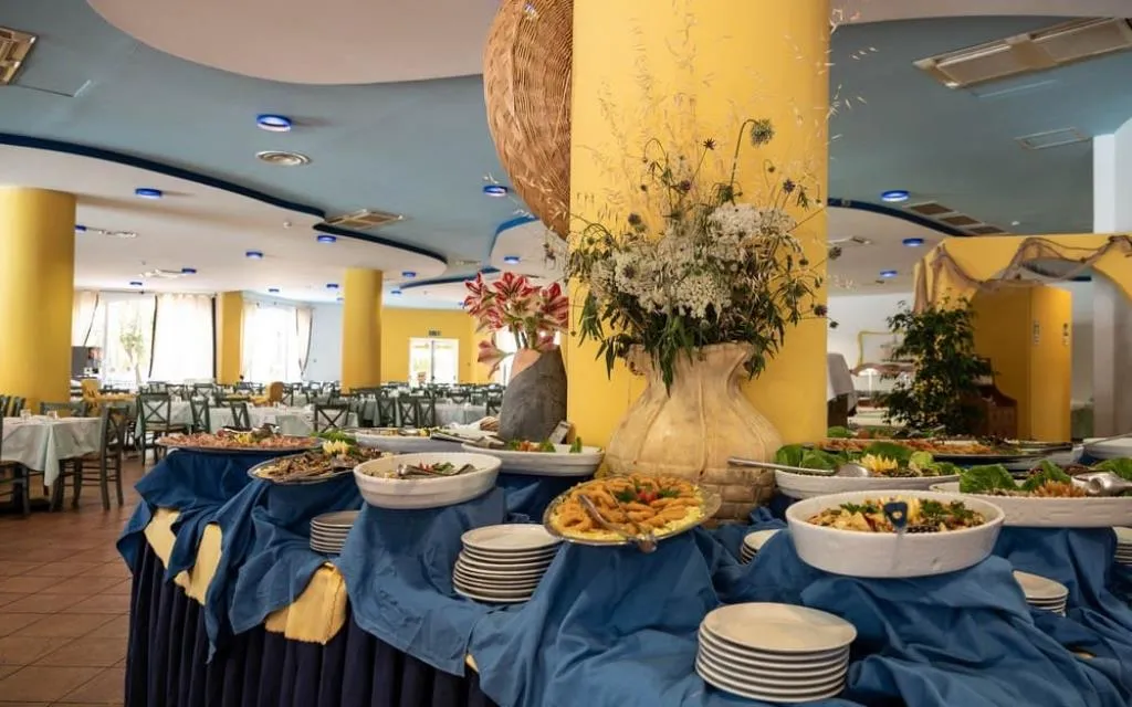 Buffet del ristorante con piatti pronti e composizione floreale centrale