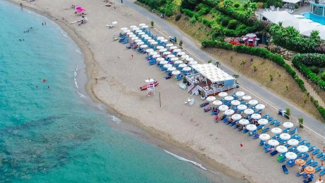 Spiaggia attrezzata vista dall'alto con file di ombrelloni e lettini