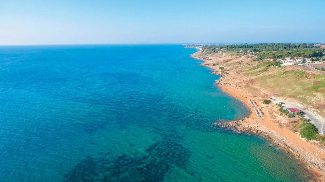Veduta aerea della costa rocciosa con mare turchese e spiaggia