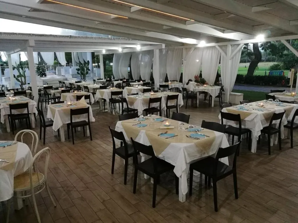 Ristorante all'aperto coperto con tavoli apparecchiati e tende bianche