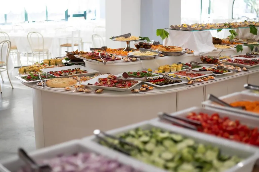 Lungo buffet con piatti di antipasti, verdure e contorni in sala luminosa