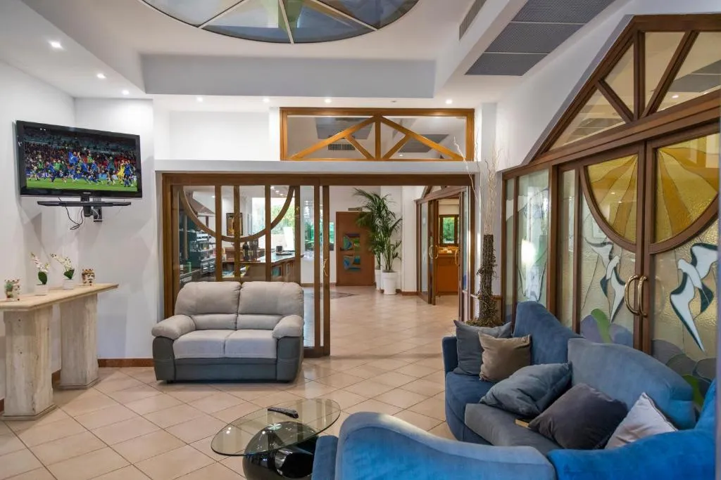 Hall dell'hotel con divani blu e grigio, TV a parete e vetrate decorate