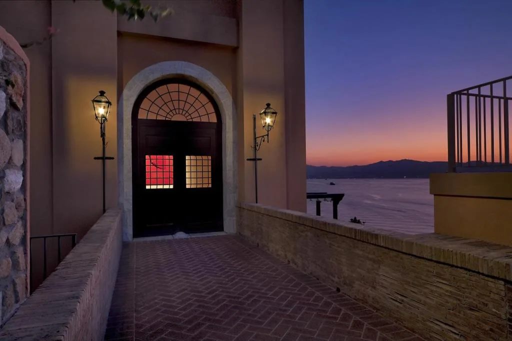 Ingresso illuminato dell'hotel con portone ad arco e lampioni al tramonto sul mare