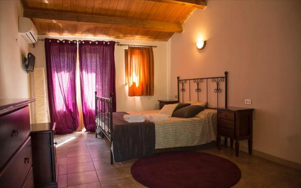 Camera con letto in ferro battuto, soffitto in legno e tende viola
