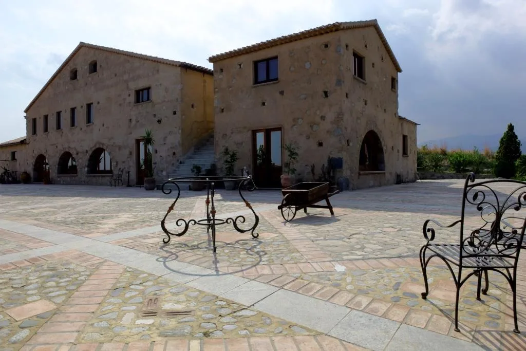 Cortile in pietra di antico casale con pavimentazione in acciottolato e arredi in ferro battuto